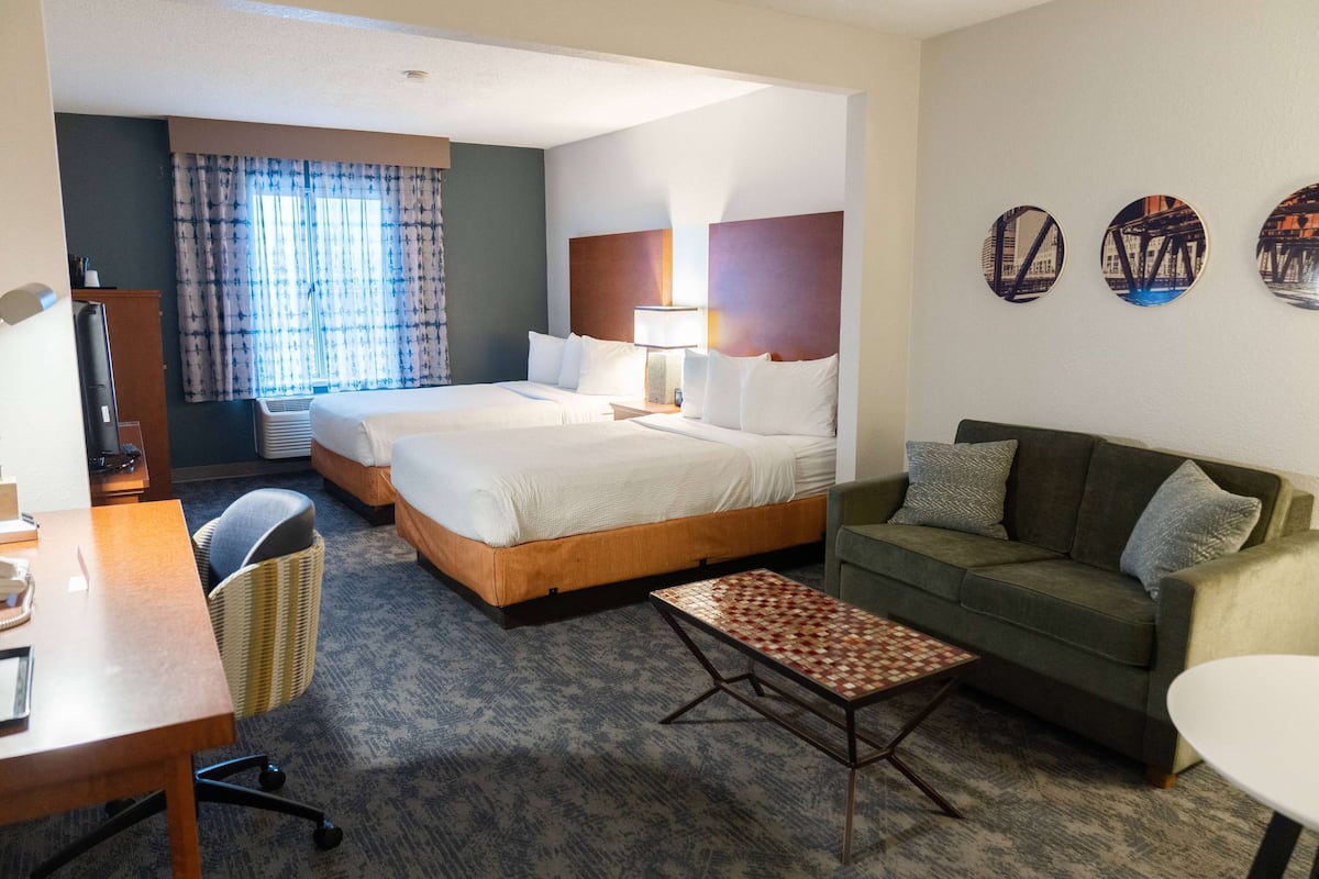Een hotelkamer met twee bedden, een bank, een bureau en een stoel.