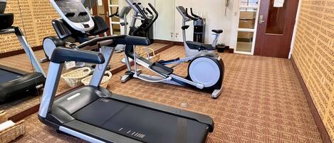 Uma academia com esteiras, elípticos e bicicleta ergométrica.