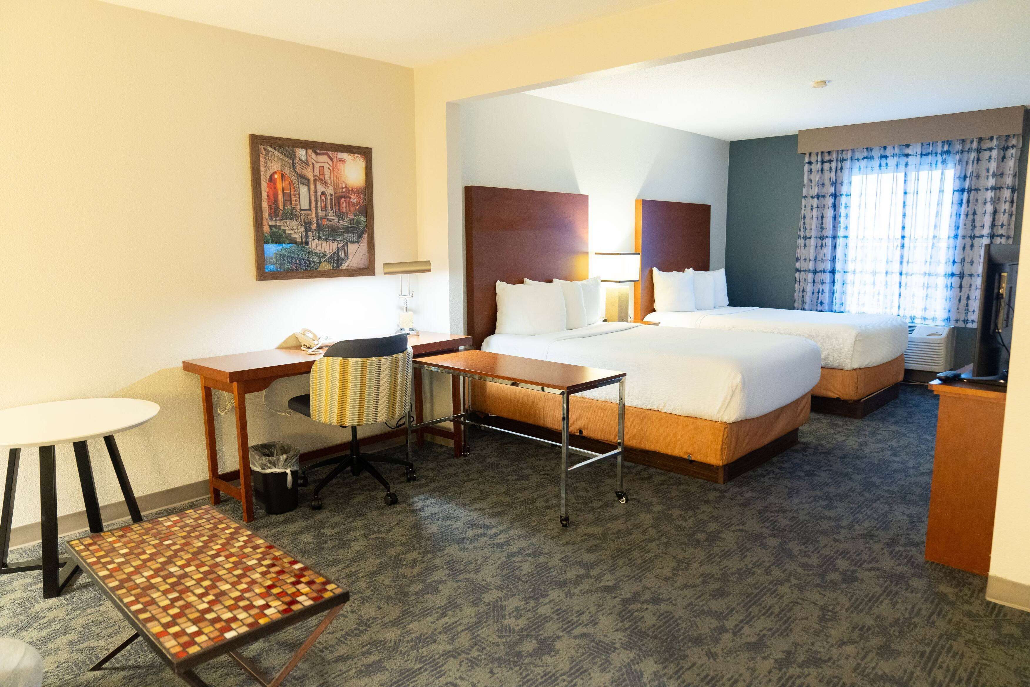 A hotel room with a bed, desk, chair, and a small table.