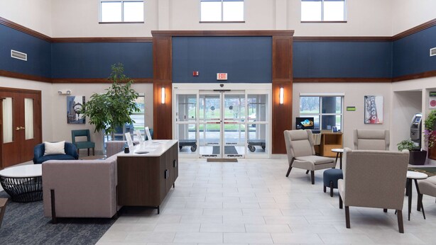 A spacious lobby with a reception desk, seating area, and a large glass door entrance. - La Quinta Inn & Suites by Wyndham Bannockburn-Deerfield (Deerfield)