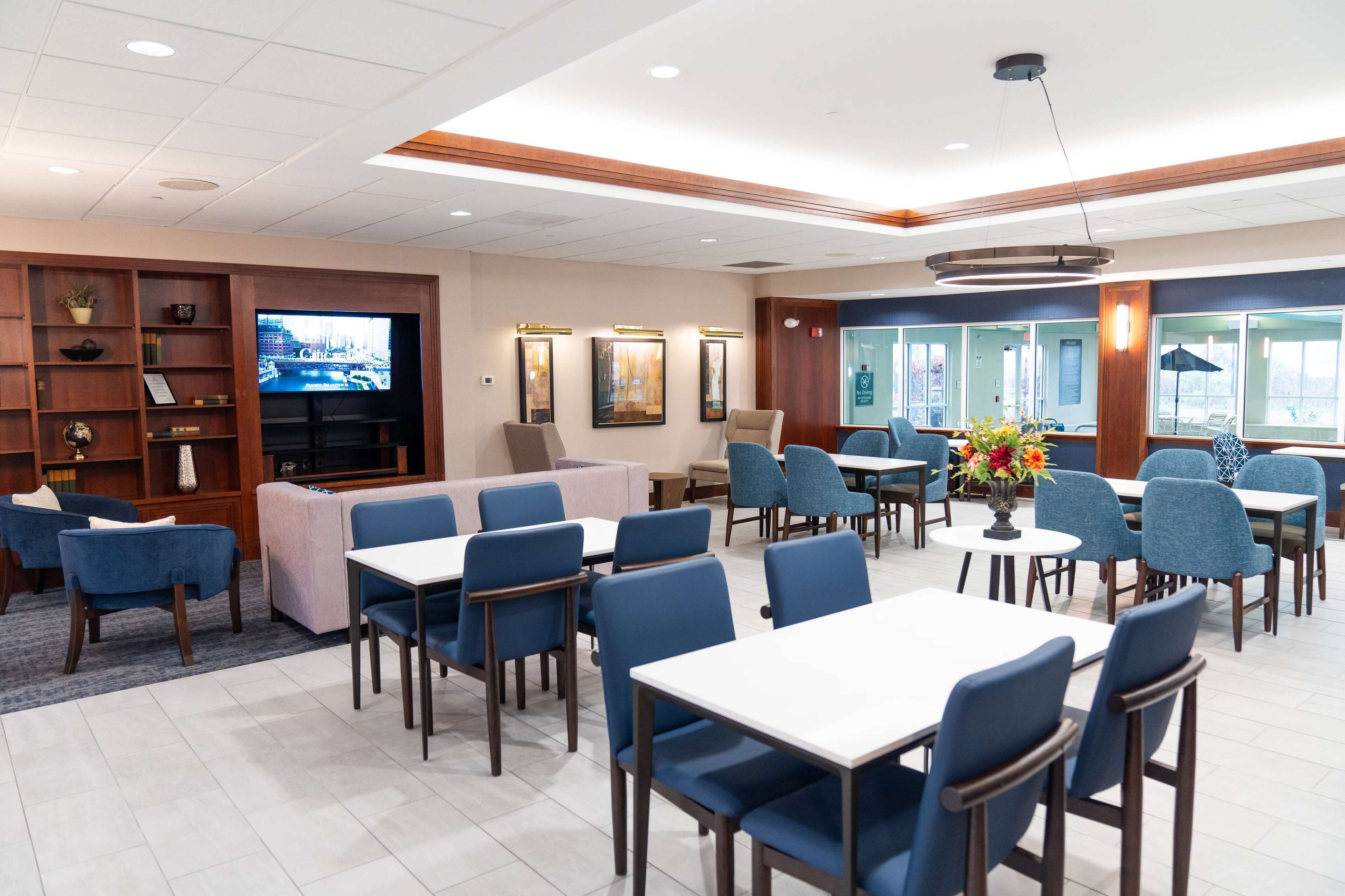 A hotel lobby with a seating area, a television, and a reception desk.