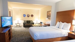 A hotel room with a large bed, a desk, a chair, a television, and a sofa. - La Quinta Inn & Suites by Wyndham Bannockburn-Deerfield (Deerfield)