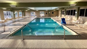 A large indoor swimming pool with multiple lounge chairs and a blue chair in the center. - La Quinta Inn & Suites by Wyndham Bannockburn-Deerfield (Deerfield)