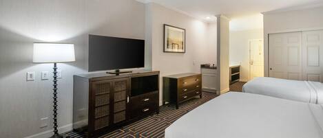 A hotel room with a bed, a desk, a television, a dresser, and a lamp.