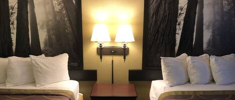 A hotel room with two beds, a nightstand, and two wall-mounted lamps.