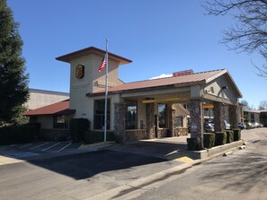 Standalone building with a prominent tower and clock, sheltered entrance and parking lot.