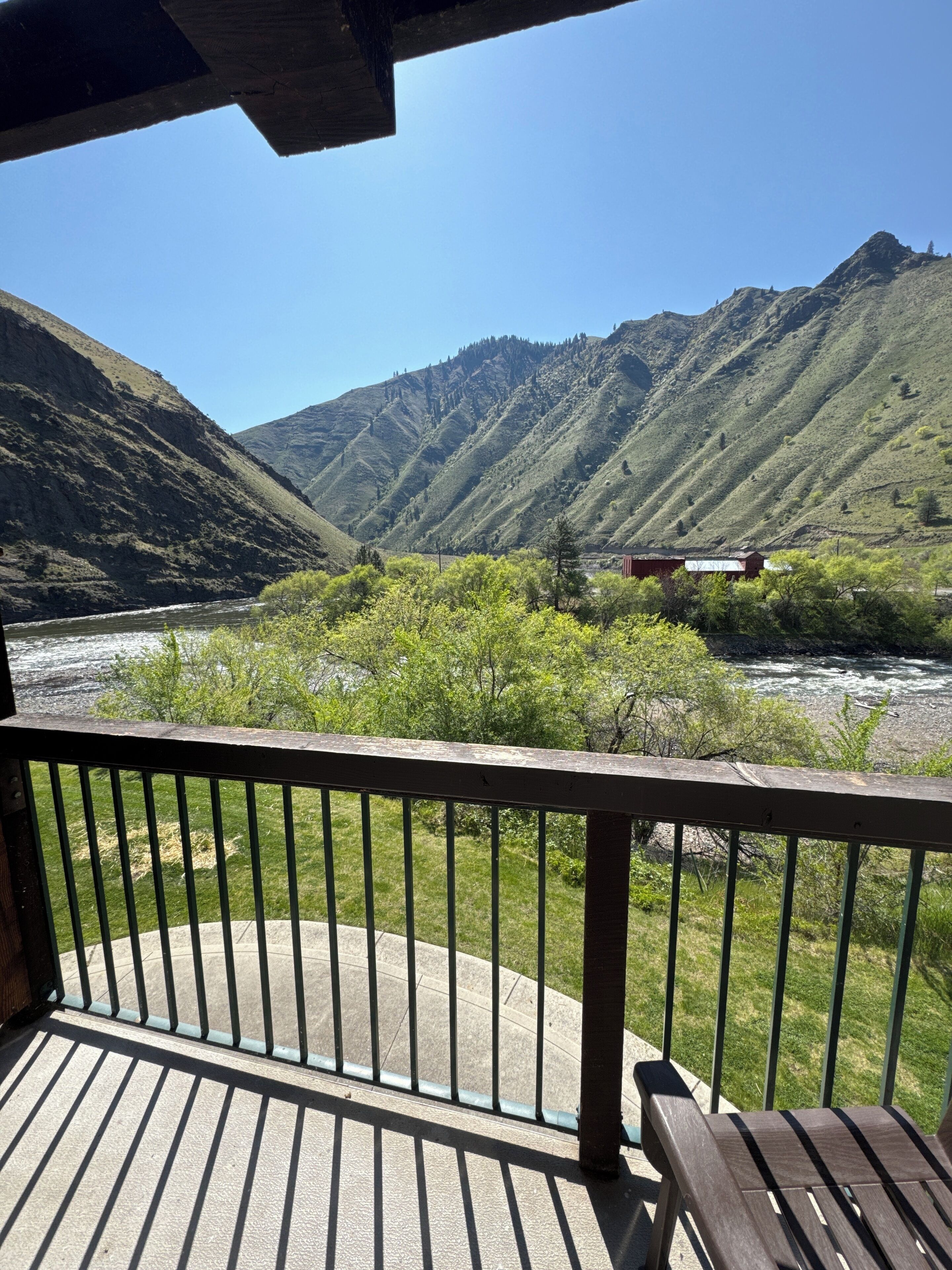 A deck with a view of a river and mountains.