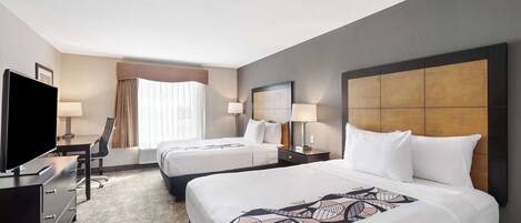 A hotel room with two beds, a TV, a desk, and a chair.