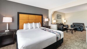 Una camera d'albergo con un letto grande, due comodini con lampade, una poltrona in pelle, un divano e un tavolino.