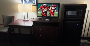 A television on a wooden stand with a remote control, a lamp, and a microwave on a cabinet. - Red Roof Inn Port Allen West LSU Stadium (Port Allen)