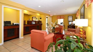 A hotel lobby with a reception desk, a seating area with striped sofas, and a television. - Motel 6 Luling, LA (Luling)