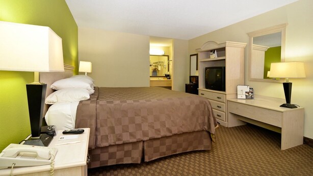 A hotel room with a bed, bedside tables, a desk with a TV, and a mirror. - Motel 6 Luling, LA (Luling)