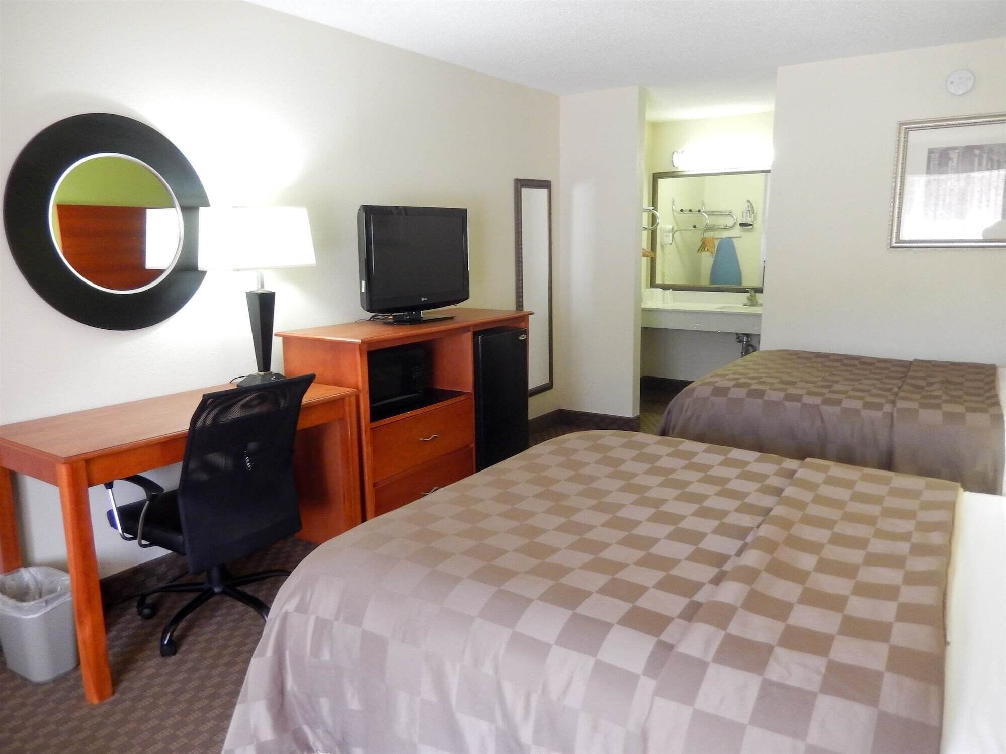 Una habitación de hotel con escritorio, silla, televisión y dos camas.