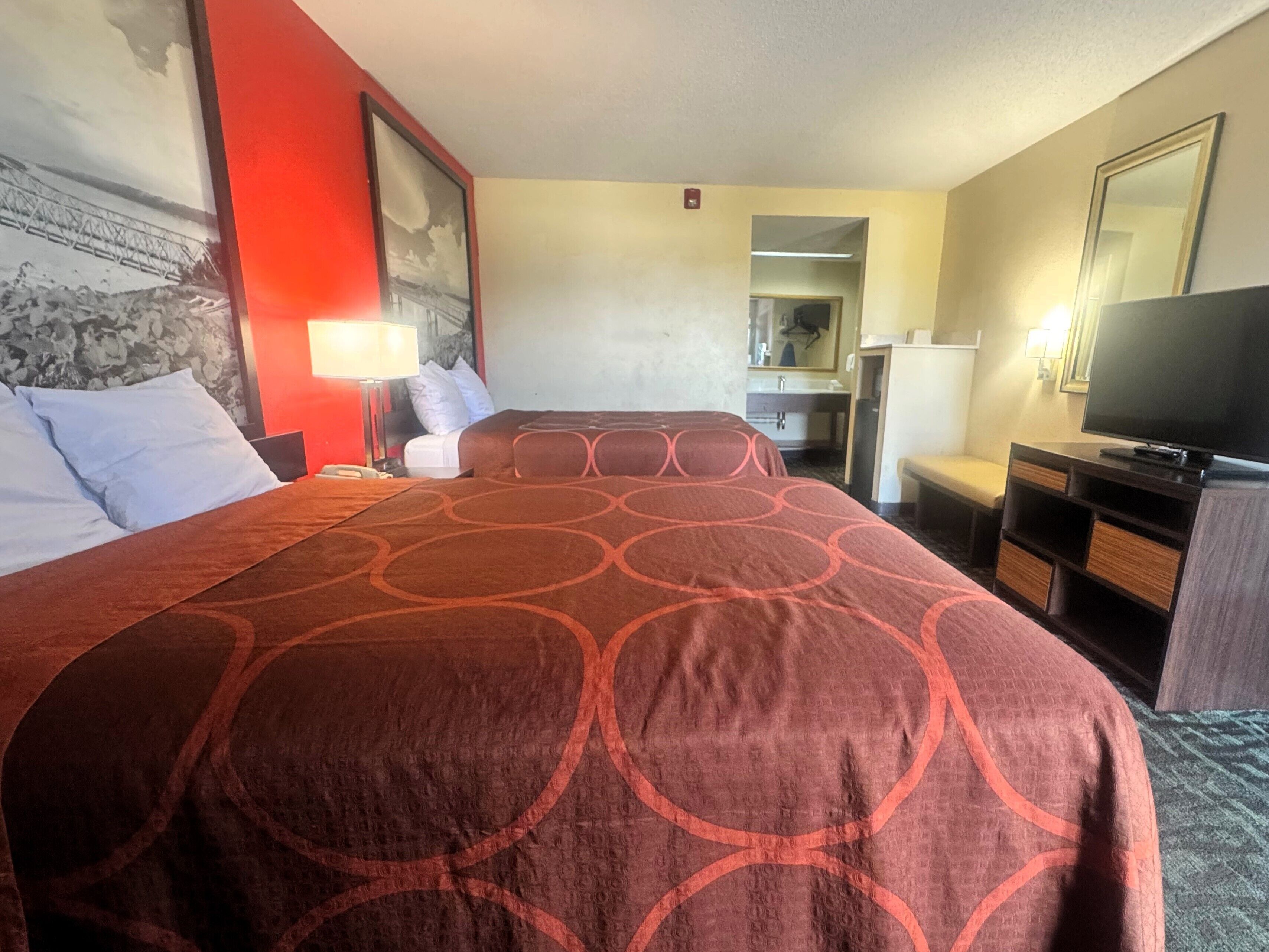 Une chambre d’hôtel avec un grand lit, un bureau, une télévision et une salle de bain visible à travers une porte ouverte.