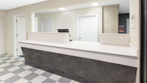 A reception area with a check-in counter, a mirror, and a door to the left.