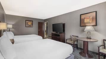 Habitación de hotel con dos camas, televisión, escritorio y una silla.