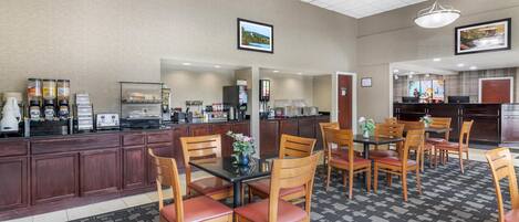 A hotel lobby with a reception desk, seating area, and a kitchen in the background.