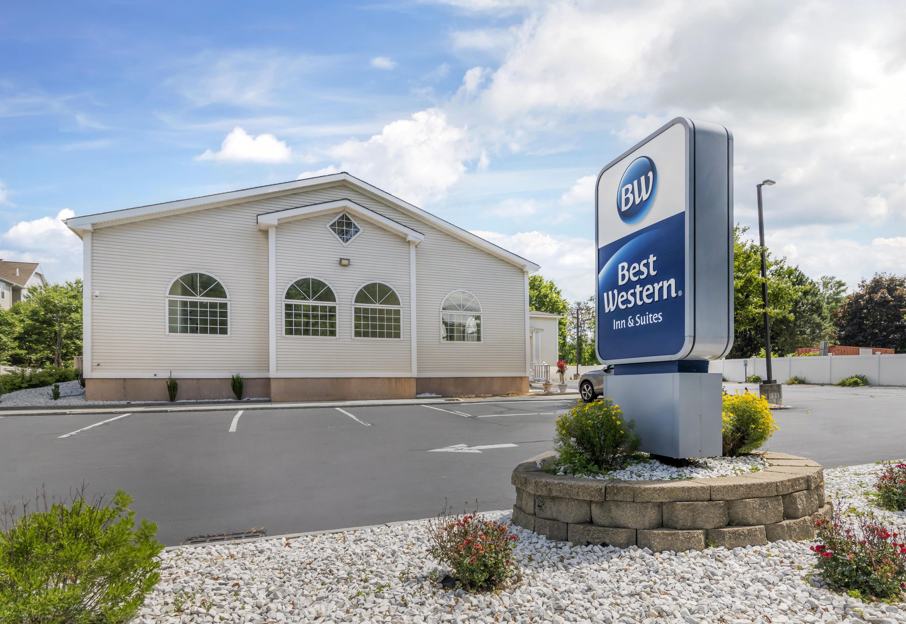 A Best Western Inn & Suites with a white exterior, large arched windows, and a signboard.