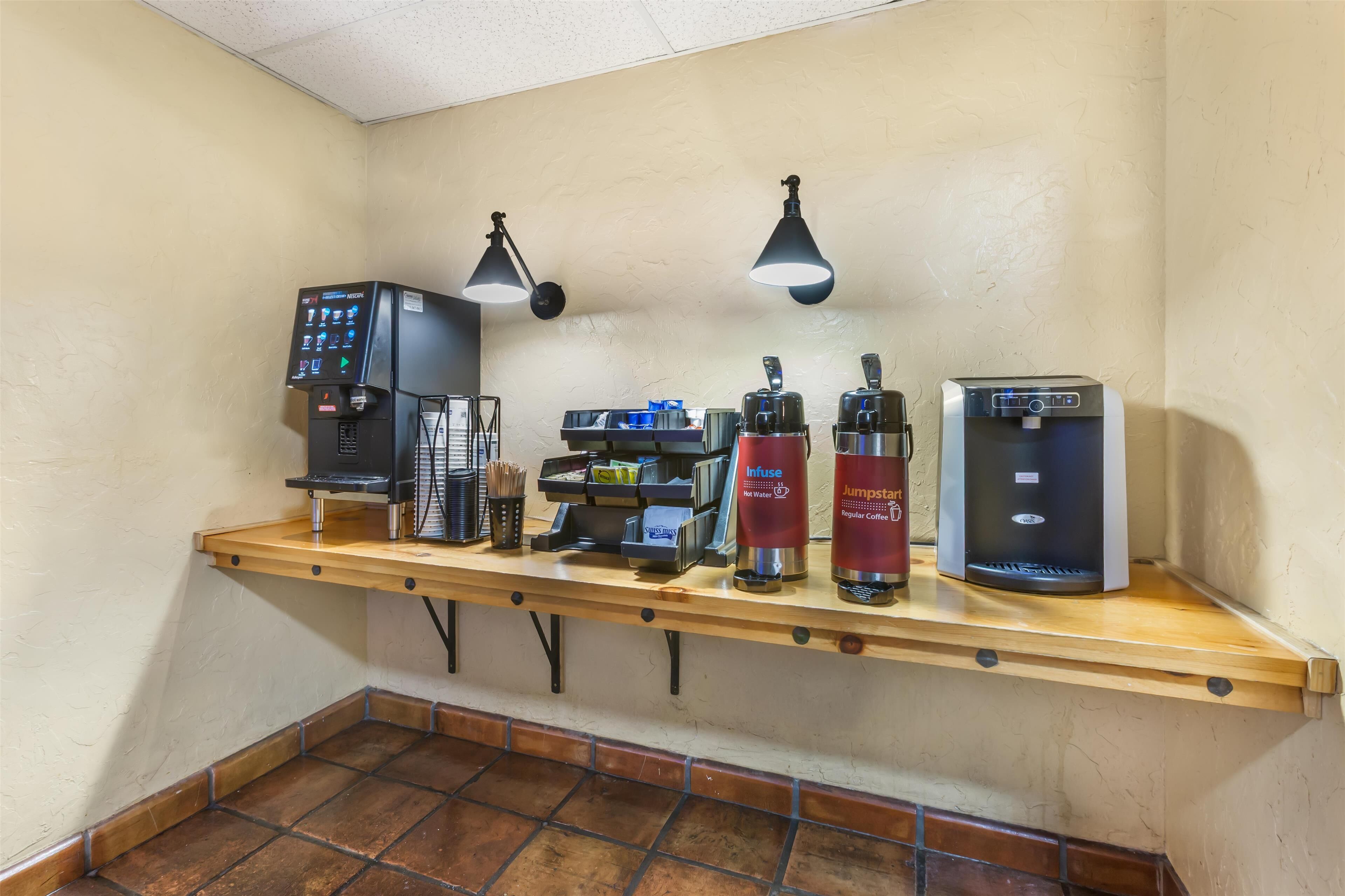 A coffee station with multiple coffee machines, a water dispenser, and a cash register.