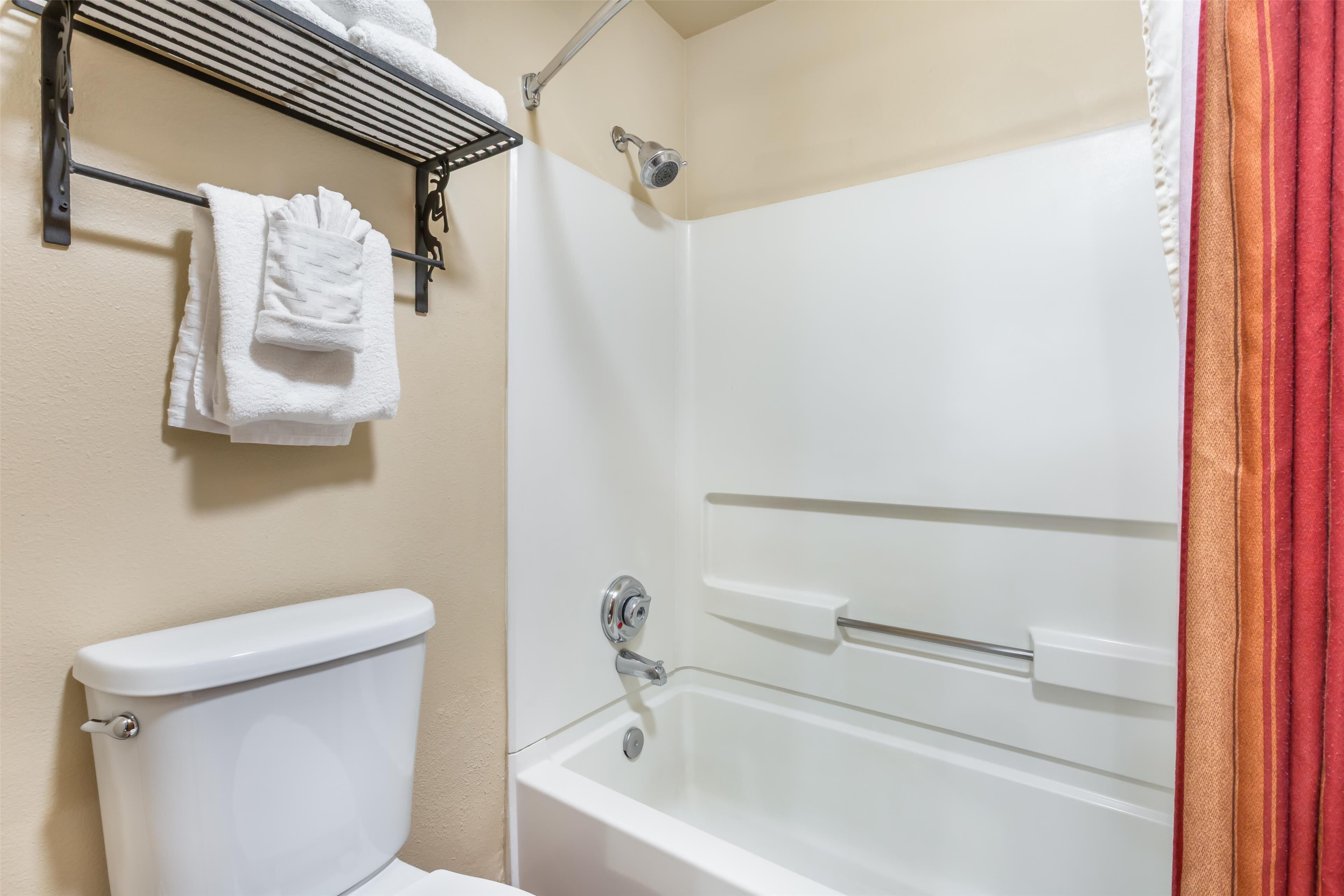 Et badeværelse med toilet, badekar og bruser.