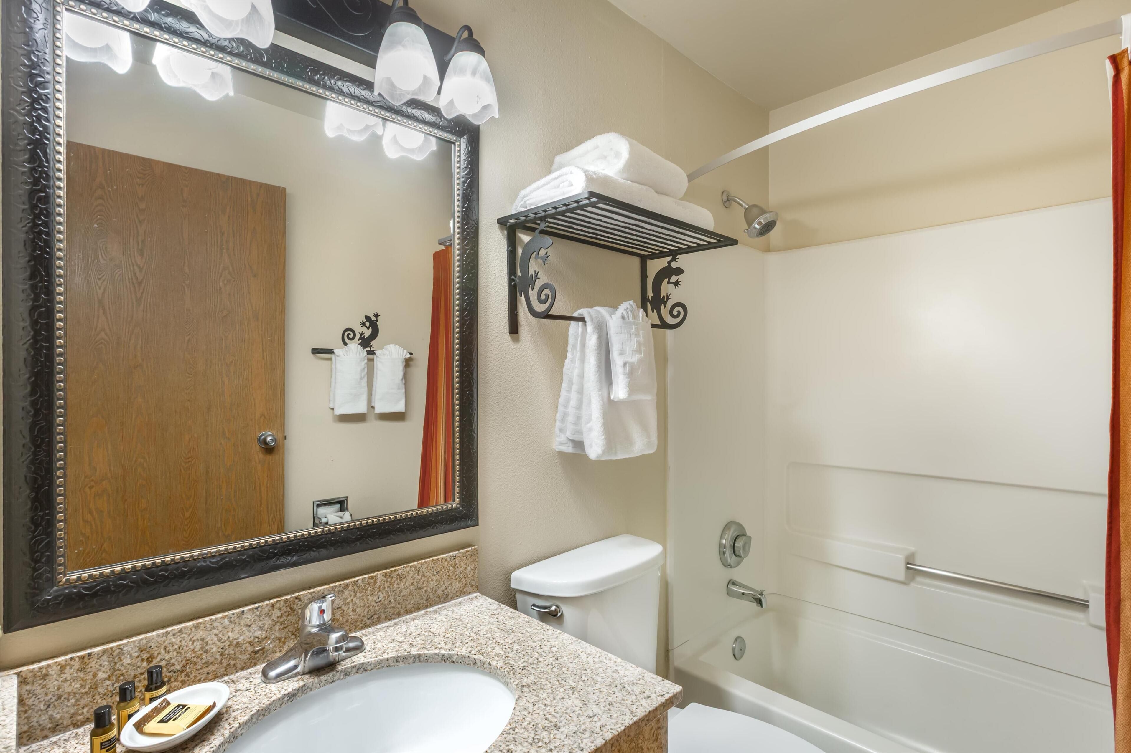 Un baño con un espejo grande, un lavabo, un inodoro y una ducha.