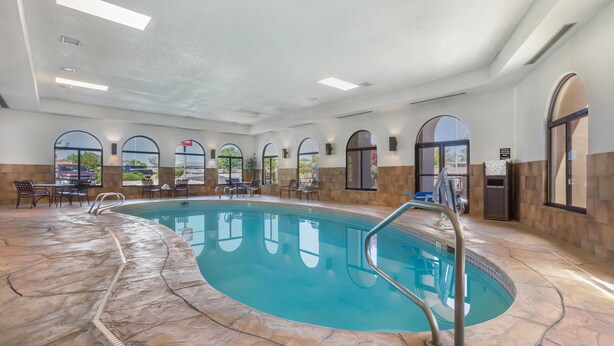 An indoor swimming pool with a stone floor, arched windows, and outdoor seating area. - Best Western Plus Inn of Santa Fe (Santa Fe)