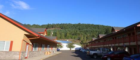A motel with a parking lot, a mountain backdrop, and a clear sky.