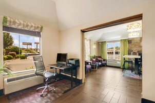 Una habitación de hotel con escritorio, silla y vista a la calle.