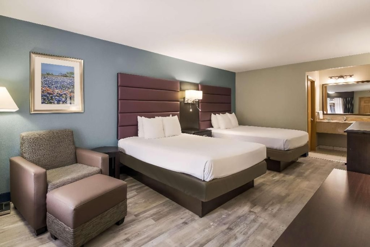A hotel room with a bed, a chair, a desk, and a mirror.