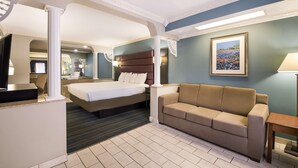 A hotel room with a bed, a sofa, a desk, and a television.