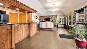 A reception area with a wooden counter, a television, and a stone wall.