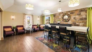 A dining area with a stone wall, a round mirror, and a bar counter.