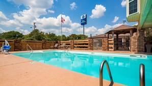 A swimming pool with lounge chairs, a covered seating area, and a sign indicating a 5 ft depth.