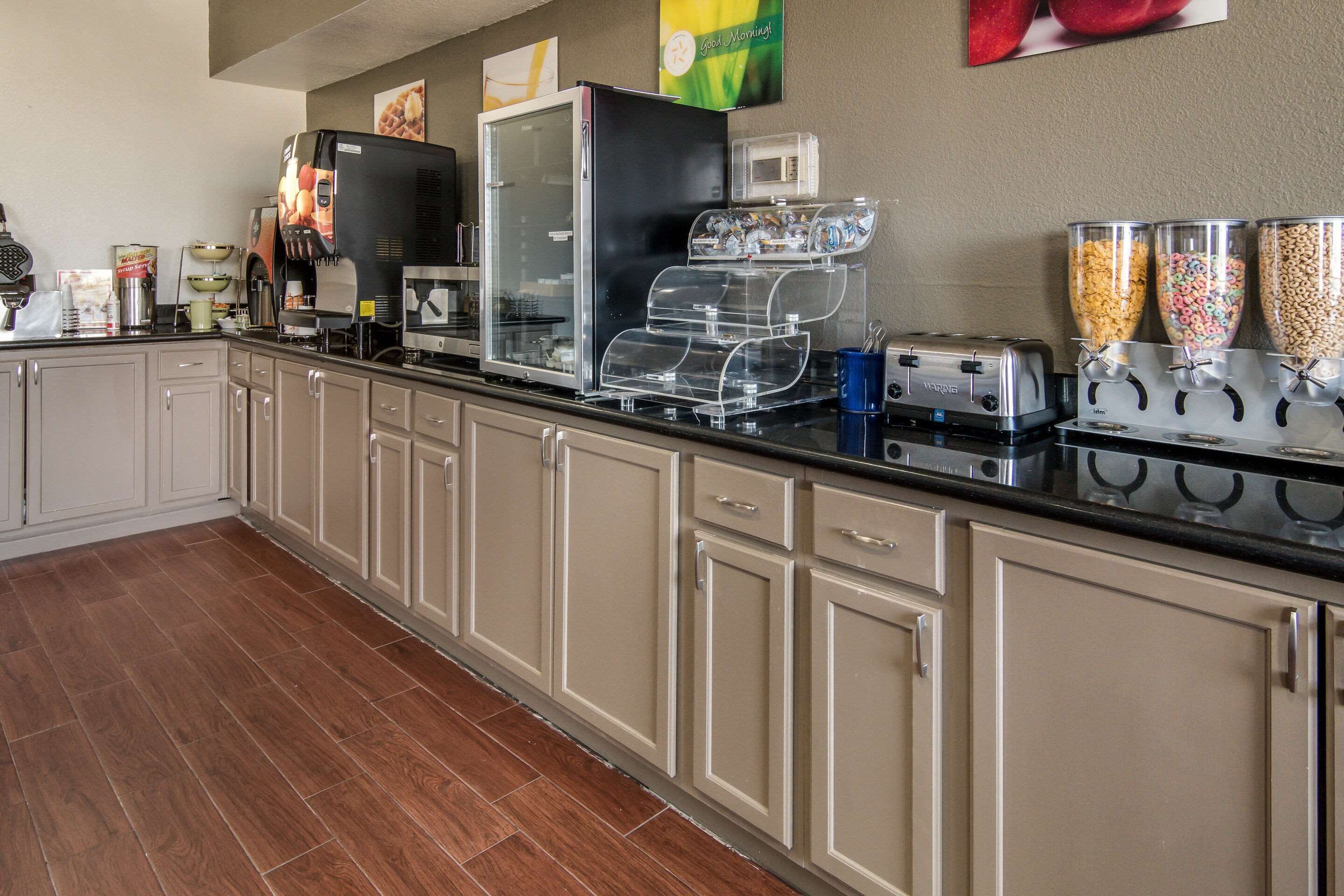 A kitchenette with a coffee machine, toaster, and cereal dispensers. - Quality Inn & Suites  Fort Worth - Fossil Creek (Fort Worth)
