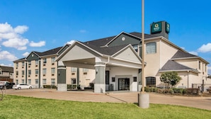 A multi-story hotel with a covered entrance and a sign indicating 'Quality'. - Quality Inn & Suites  Fort Worth - Fossil Creek (Fort Worth)