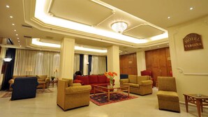 Un hall d’hôtel au design moderne, comprenant un espace de détente central avec des canapés et des fauteuils, un lustre et une enseigne indiquant le nom de l’hôtel.