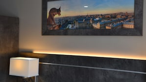 Un cuadro con una vista urbana en una pared, una lámpara moderna y una pared con textura.