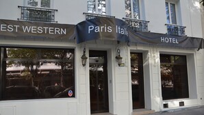 Fachada de hotel con letreros que indican 'Paris Italia Hotel' y 'EST WESTERN'.