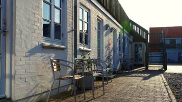 A building with a brick facade, multiple windows, and outdoor seating with metal chairs and tables.