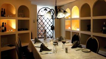 A dining area with a table set for four, wine glasses, and bottles on shelves.