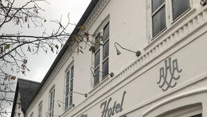 Ein Gebäude mit der Aufschrift 'Hars Hotel' über dem Eingang, mit einer blauen Tür und mehreren Fenstern.