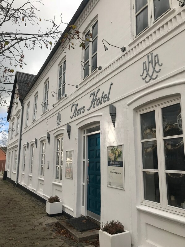 A building with the sign 'Hars Hotel' above the entrance, featuring a blue door and multiple windows.