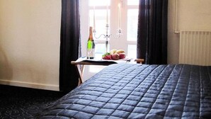 Ein Hotelzimmer mit einem Bett, einem Tisch mit Flasche, Gläsern und Obst.