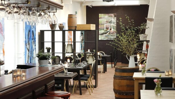 Ein Restaurant Innenraum mit Barbereich, Esstischen, Stühlen und verschiedenen Dekorationselementen.