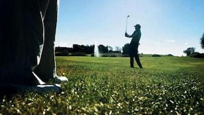 A golf course with a clear sky and a golfer in the distance.