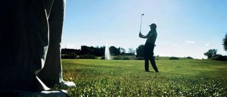 Un campo de golf con cielo despejado y un golfista a lo lejos.
