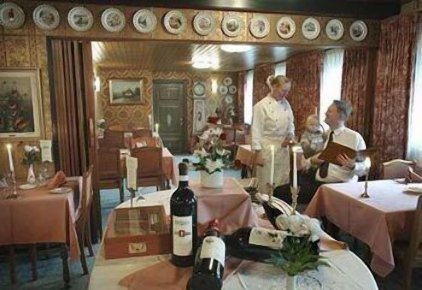 A dining area with tables set for a meal, a bottle of wine, and a bouquet of flowers on the table.