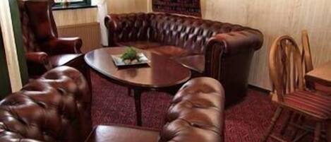 Una habitación con un sofá de cuero, una mesa de comedor de madera y una alfombra estampada.