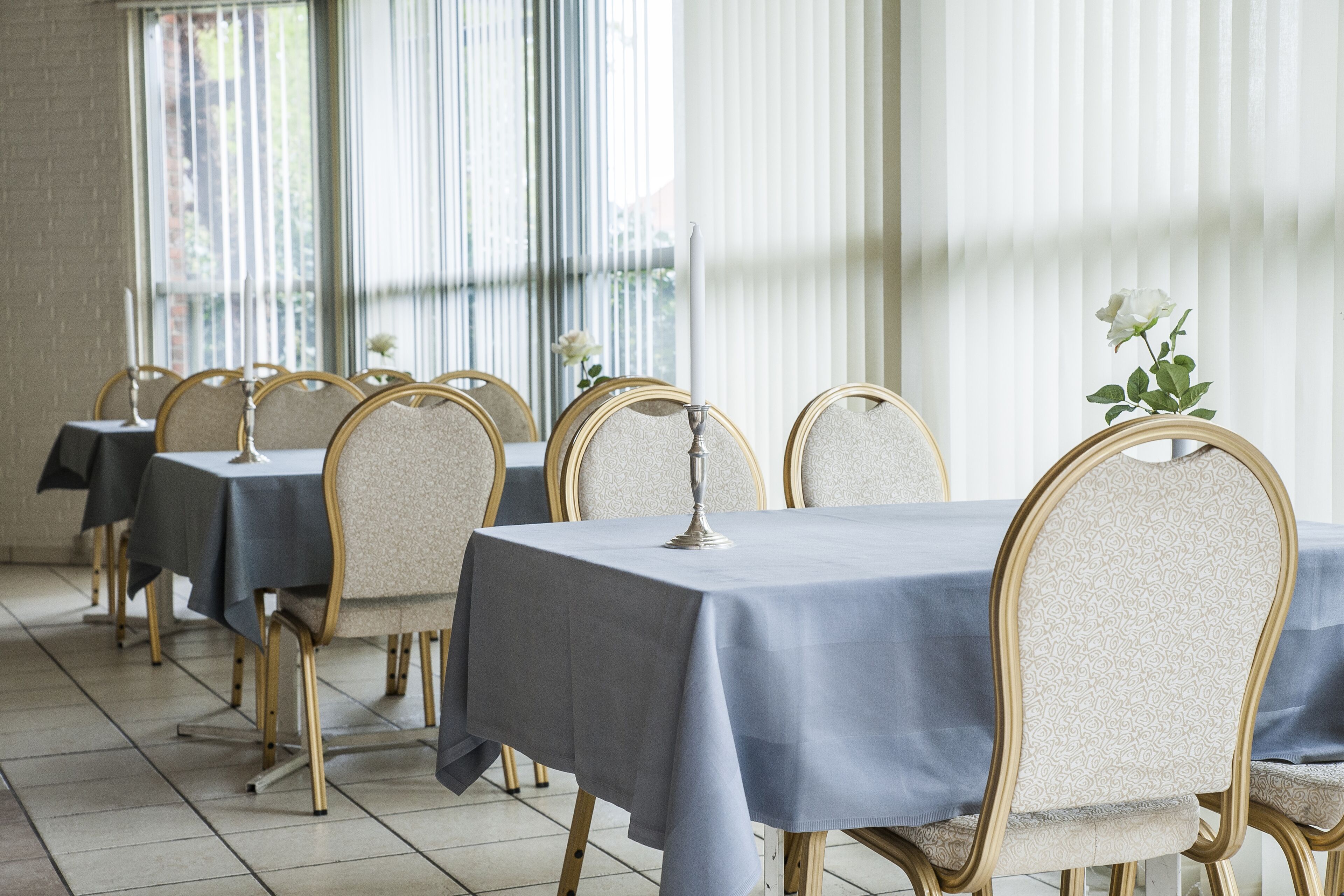 Comedor con mesas cubiertas de manteles azules y sillas doradas.