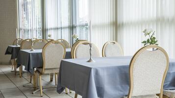 Comedor con mesas cubiertas de manteles azules y sillas doradas.